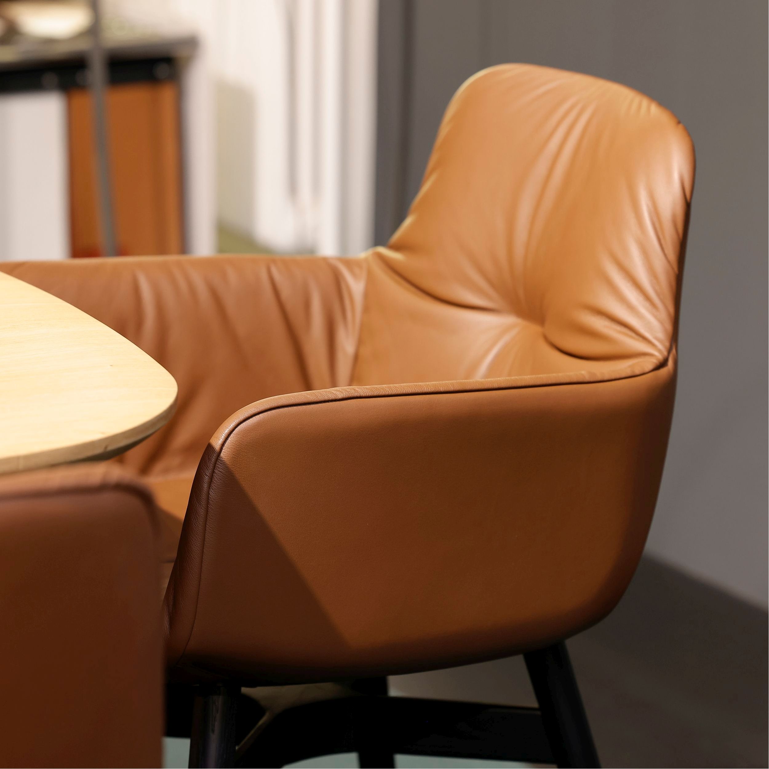Brauner Lederstuhl mit schwarzen Holzbeinen, Leya Armchair high von Freifrau, elegant und modern im Design.  