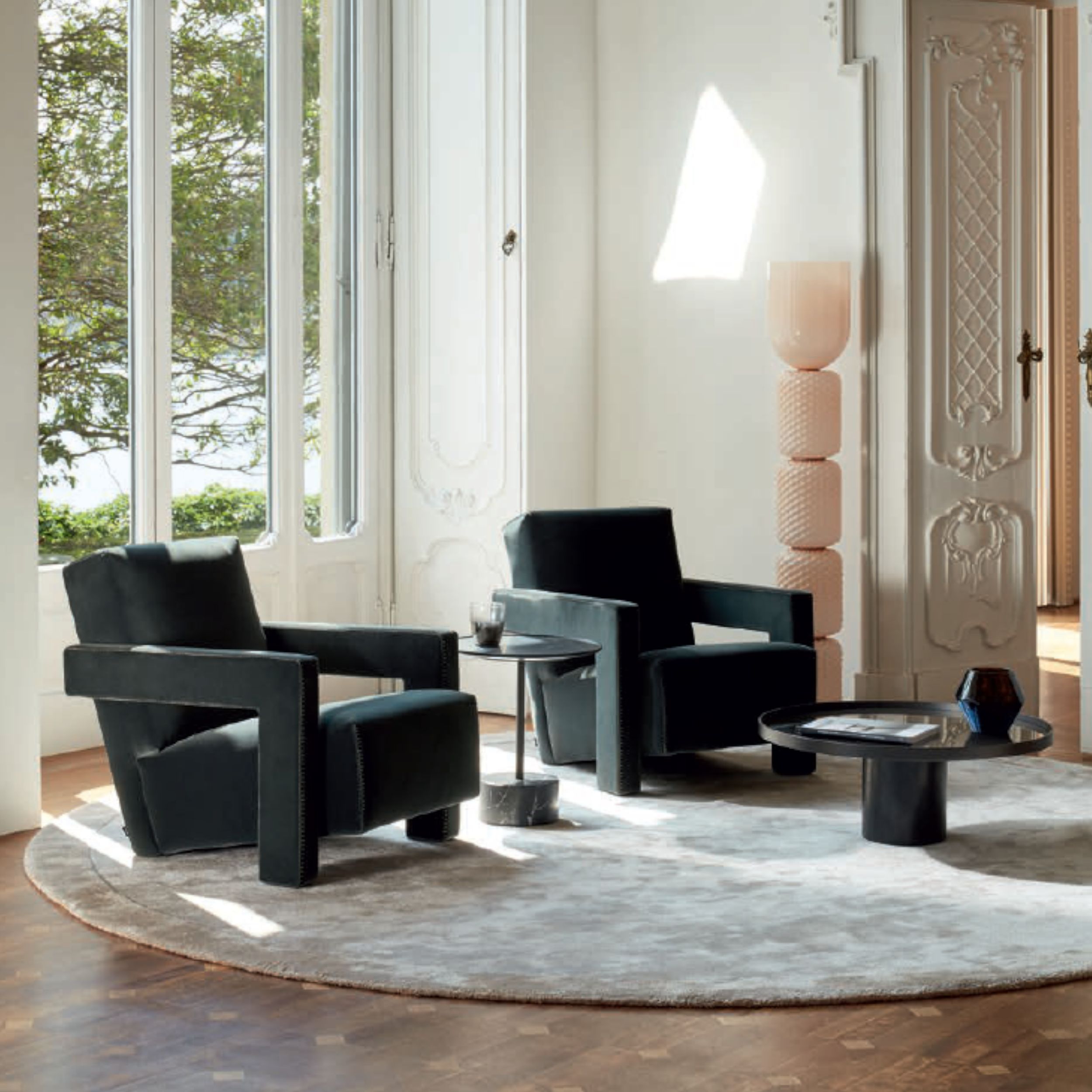 Klassisch-eleganter Wohnraum mit zwei modernen grün gepolsterten Sesseln "Utrecht" von Cassina auf einem runden, hellen Teppich.