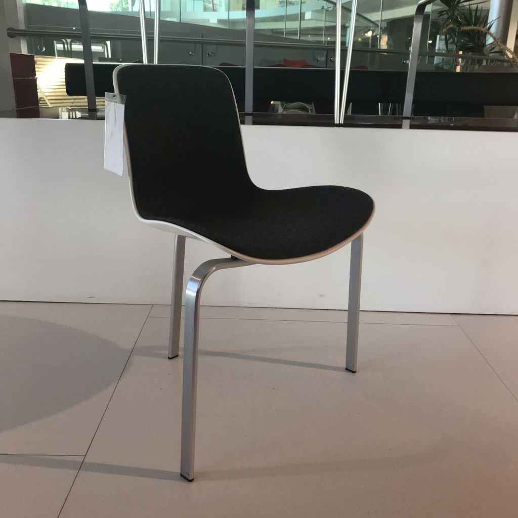 Ein dreibeiniger Stuhl, Modell PK8 von Fritz Hansen.
Der Stuhl hat eine weiße Kunststoff-Sitzschale, gepolstert mit grau meliertem Wollfilz. Die drei Metallbeine sind matt gebürstet.
