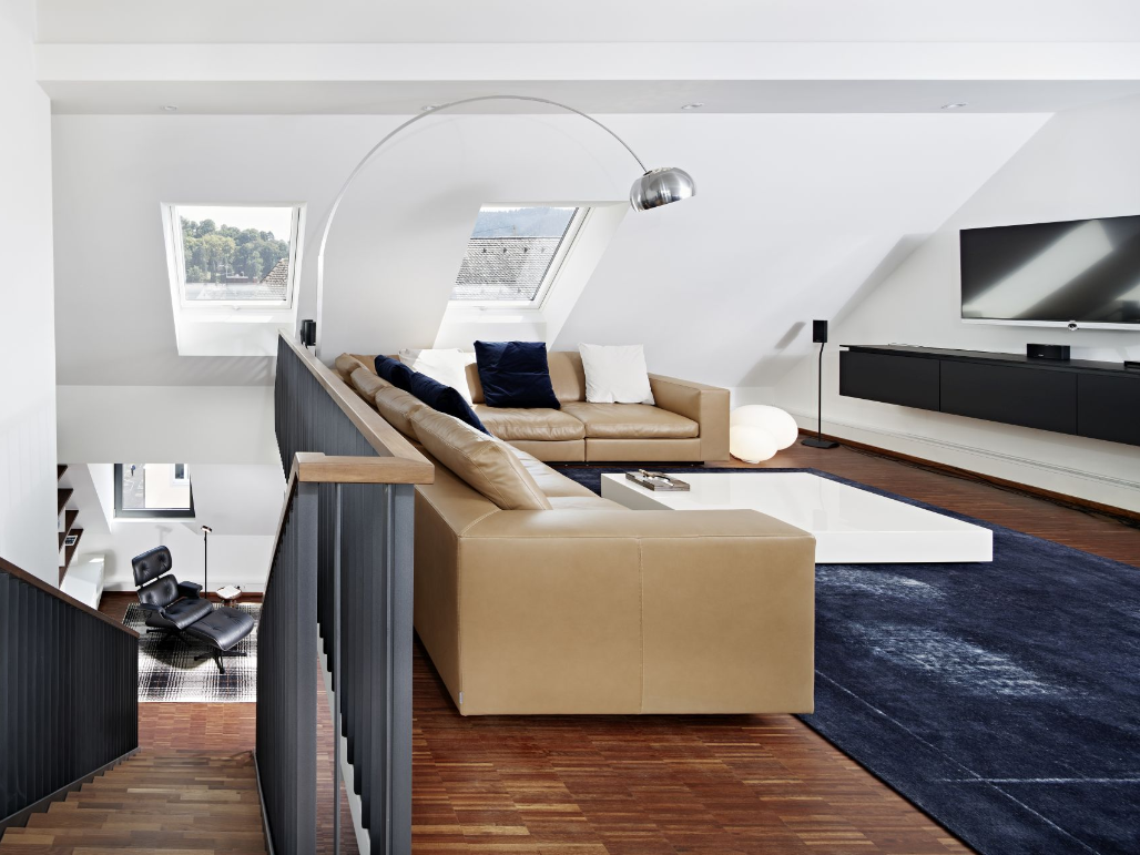 Dachgeschoss-Wohnraum mit Bogenleuchte, Ledersofa und Sideboard