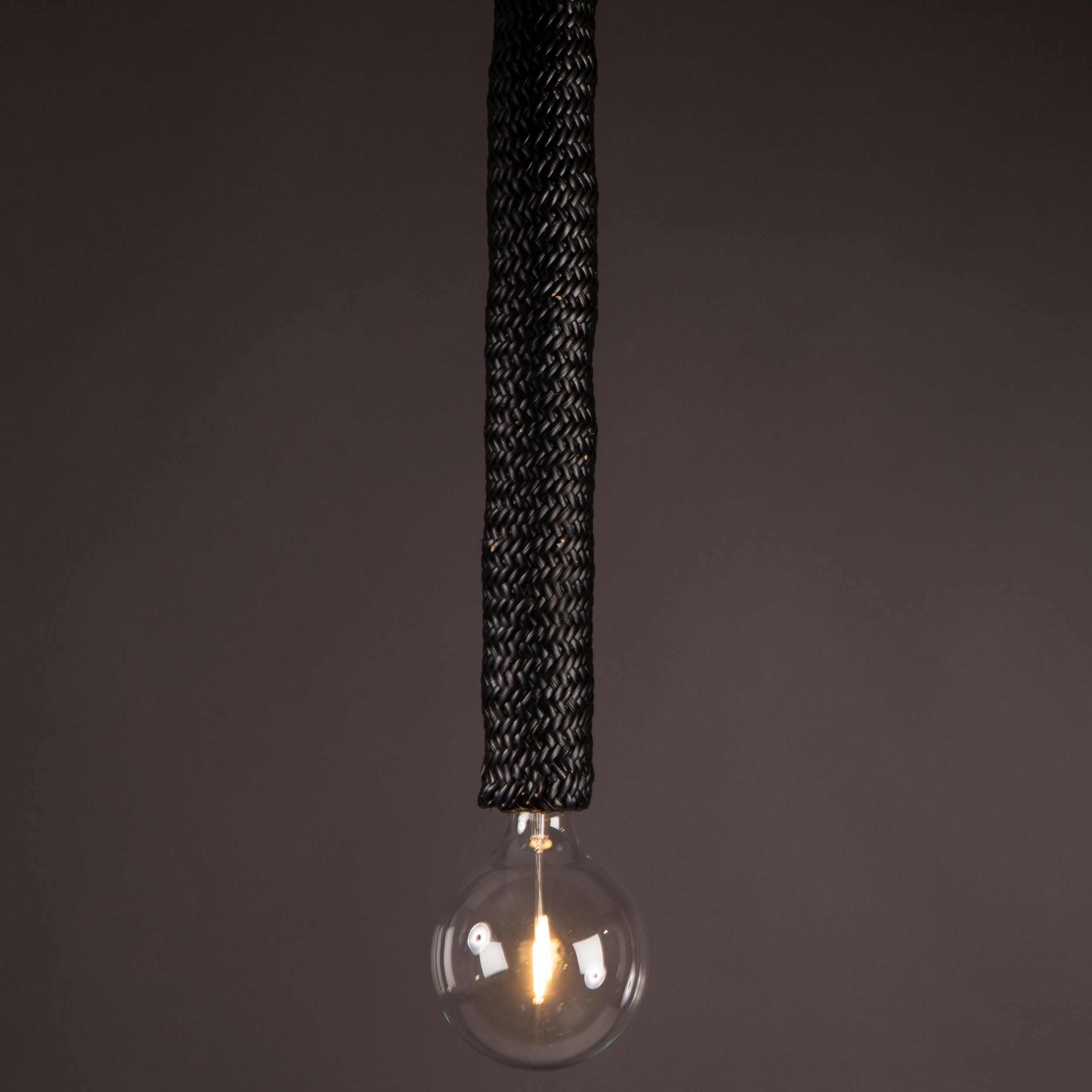 Detailansicht einer modernen schwarzen Hängelampe im Boho-Stil mit langem Flechtkorpus und runder Globe-Glühlampe.