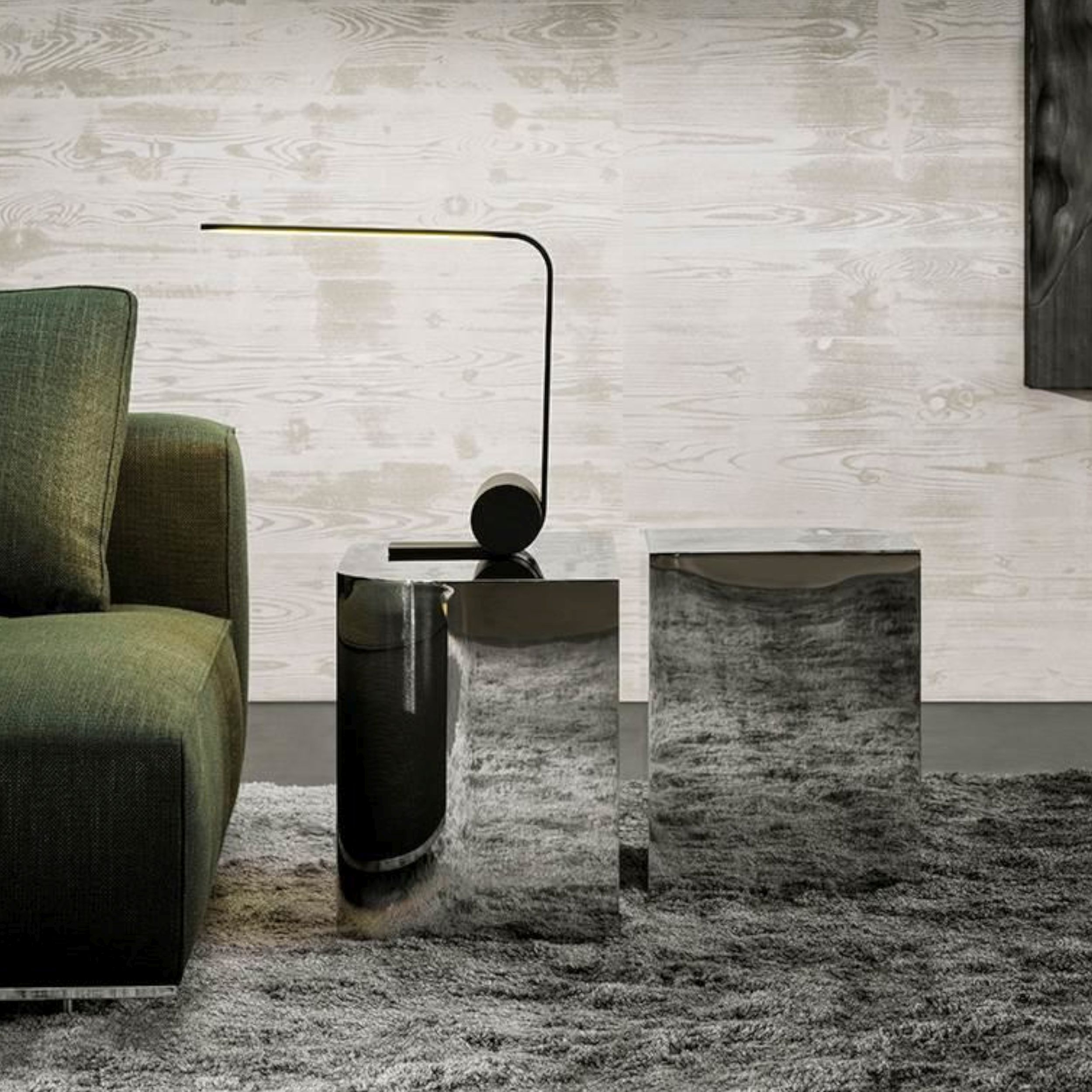 Elegantes Wohnzimmer mit grünem Sofa, einer Lampe und den verchromten Beistelltischen James von Minotti.
