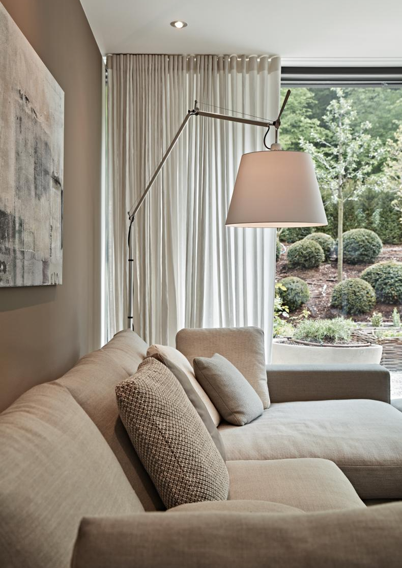 Sofa mit Kissen und Stehleuchte vor einem Vorhang