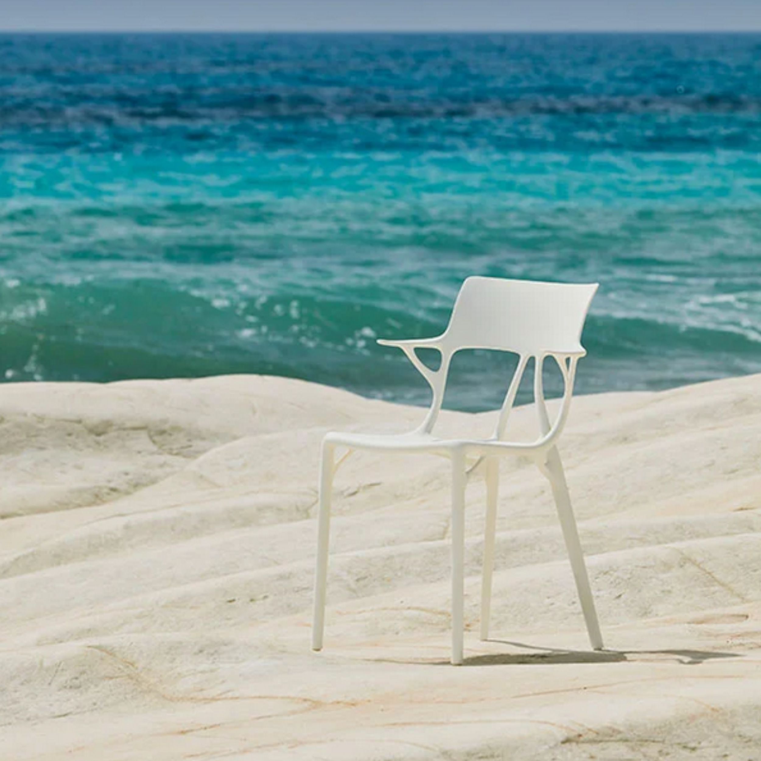 Gartenstuhl A.I. von Kartell in weiß im Milieubild am Strand.