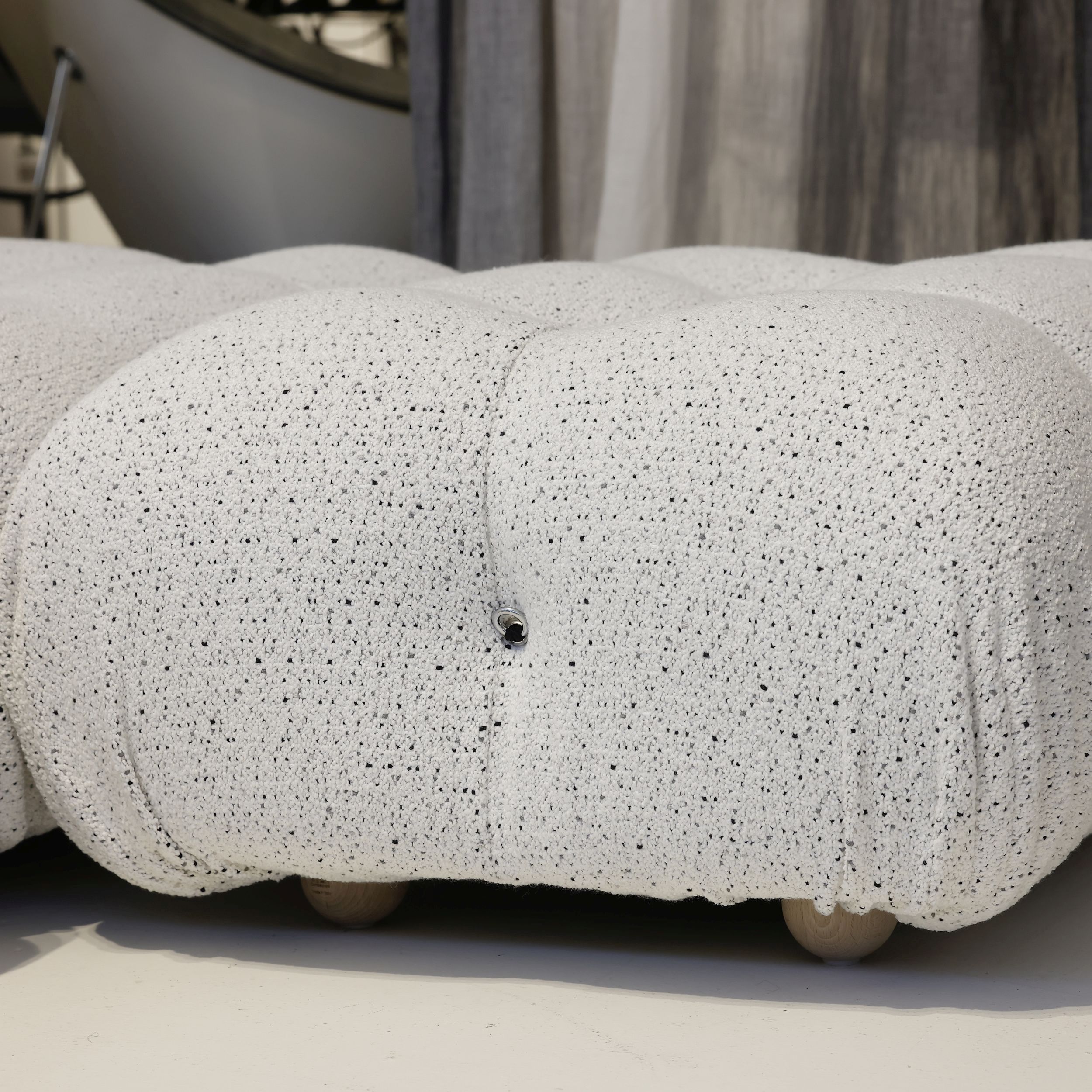 Das Bild zeigt in Nahaufnahme einen Hocker aus dem modularen Sofaprogramm Camaleonda von B&B Italia. Der Hocker ist mit weißem Stoff bezogen.