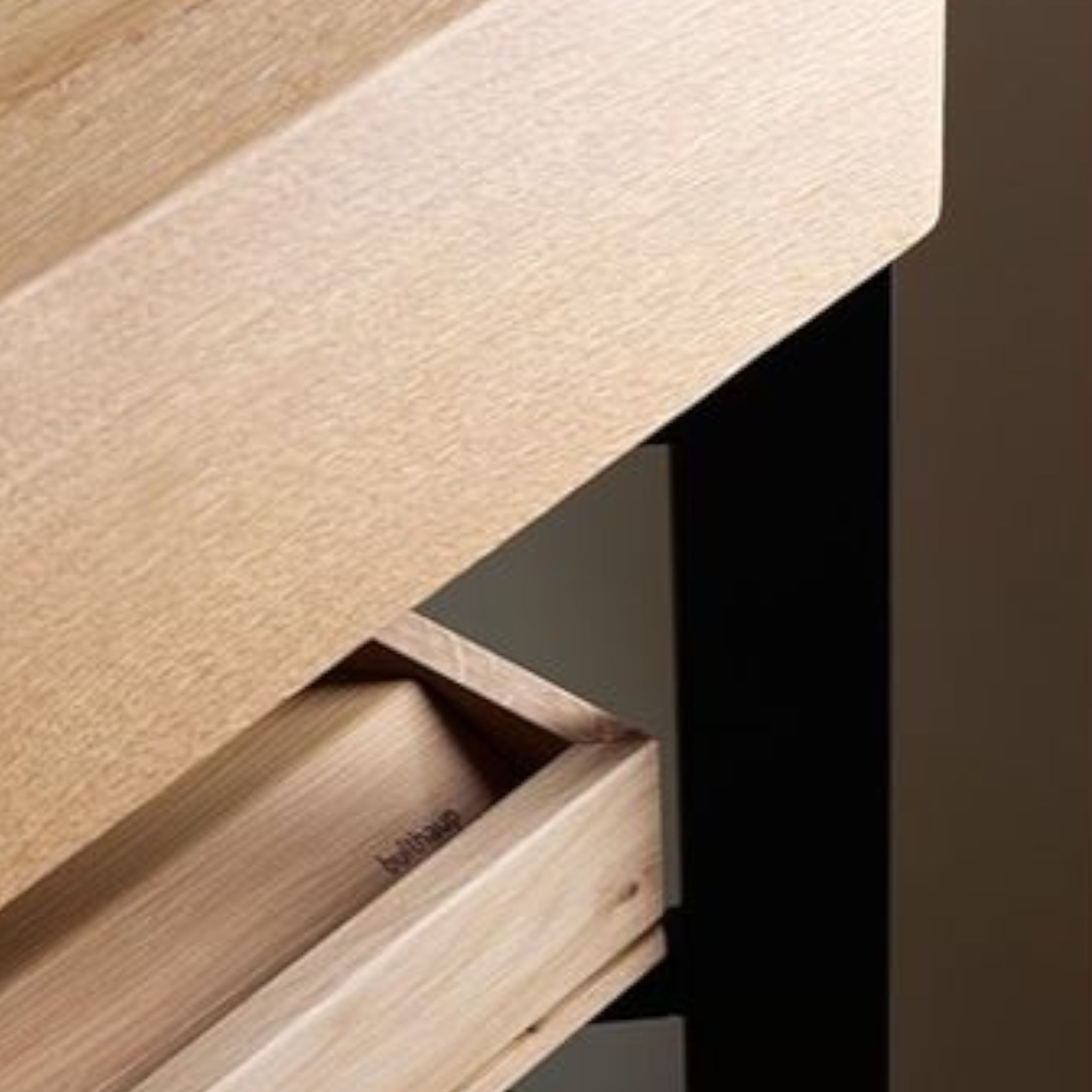 Zu sehen ist eine Detailaufnahme eines schwarzen Metallrahmen-Elements mit massiver Eichen-Abdeckplatte.