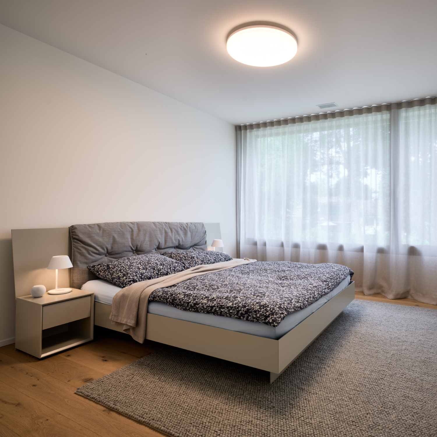 Schlafzimmer mit Polsterbett, Deckenleuchte und bodentiefem Vorhang