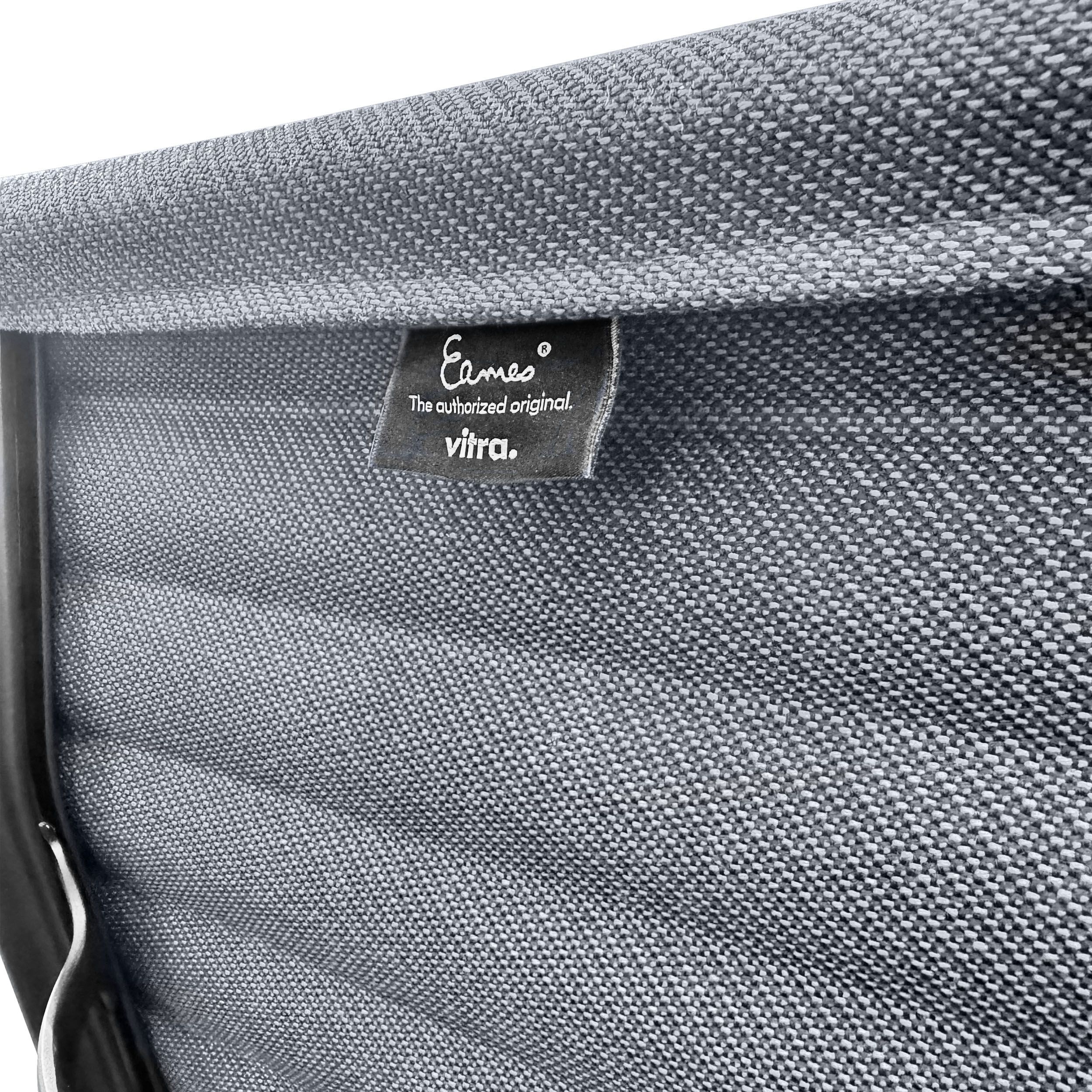 Bürostuhl EA119 von Vitra mit blauem Stoffbezug und schwarzem Gestell als Detailaufnahme des Labels auf der Rückseite der Lehne.