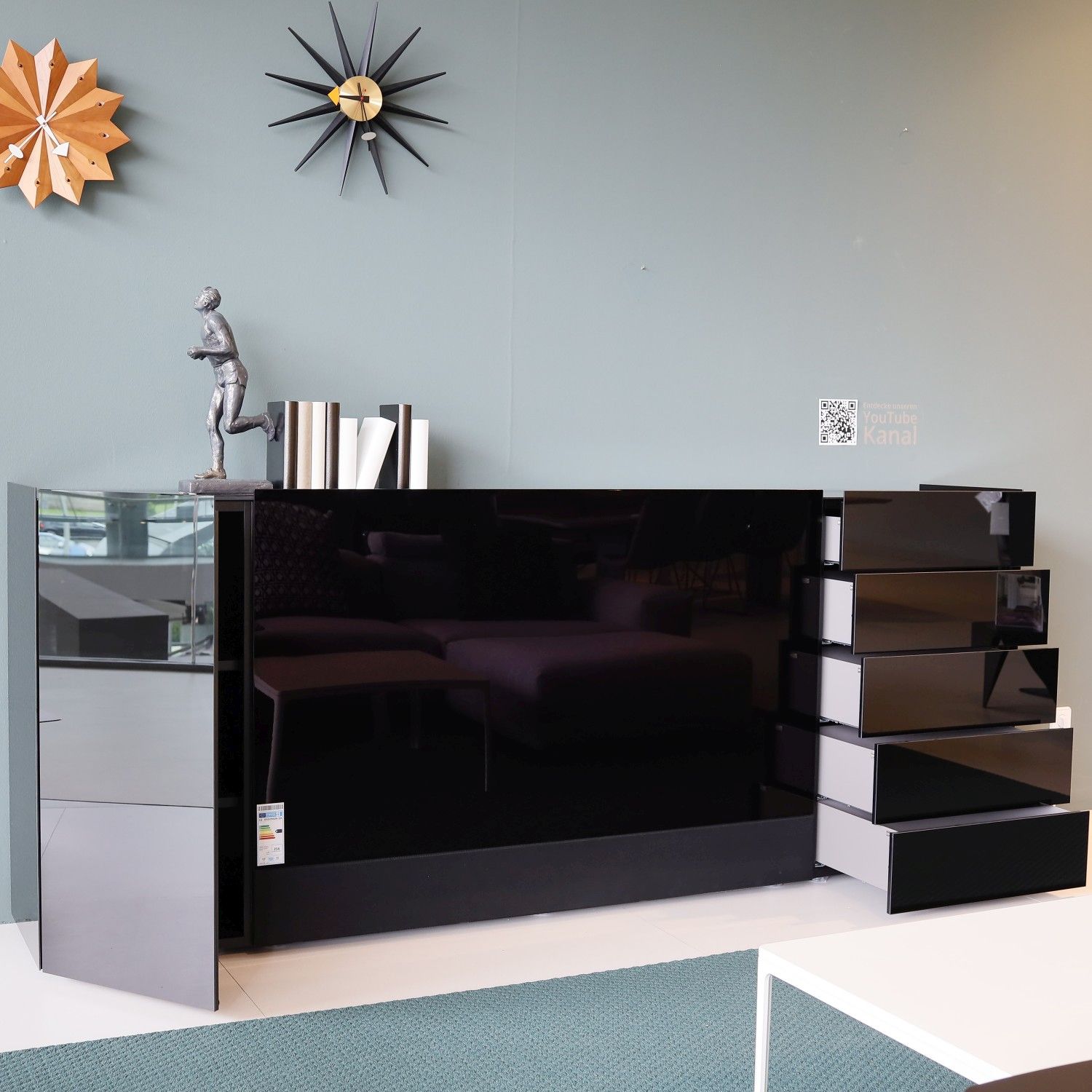 Sideboard Jorel von Interlübke mit integriertem TV in Glas schwarz im Milieubild, Fronten geöffnet.
