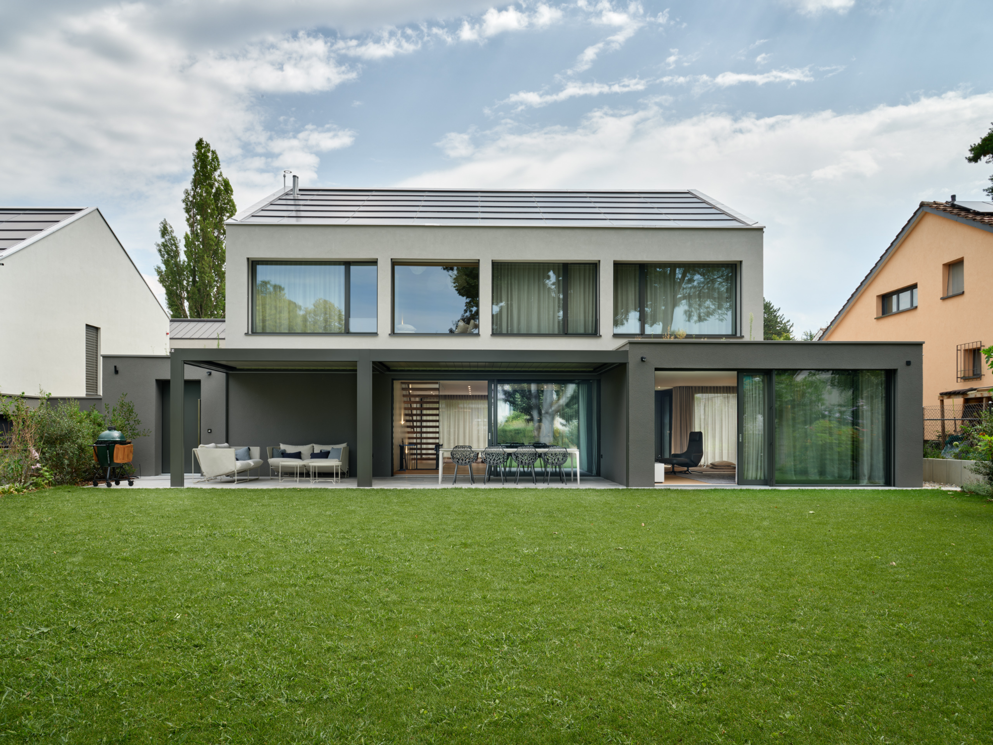 Modernes Wohnhaus mit grauer Fassade und Rasenfläche