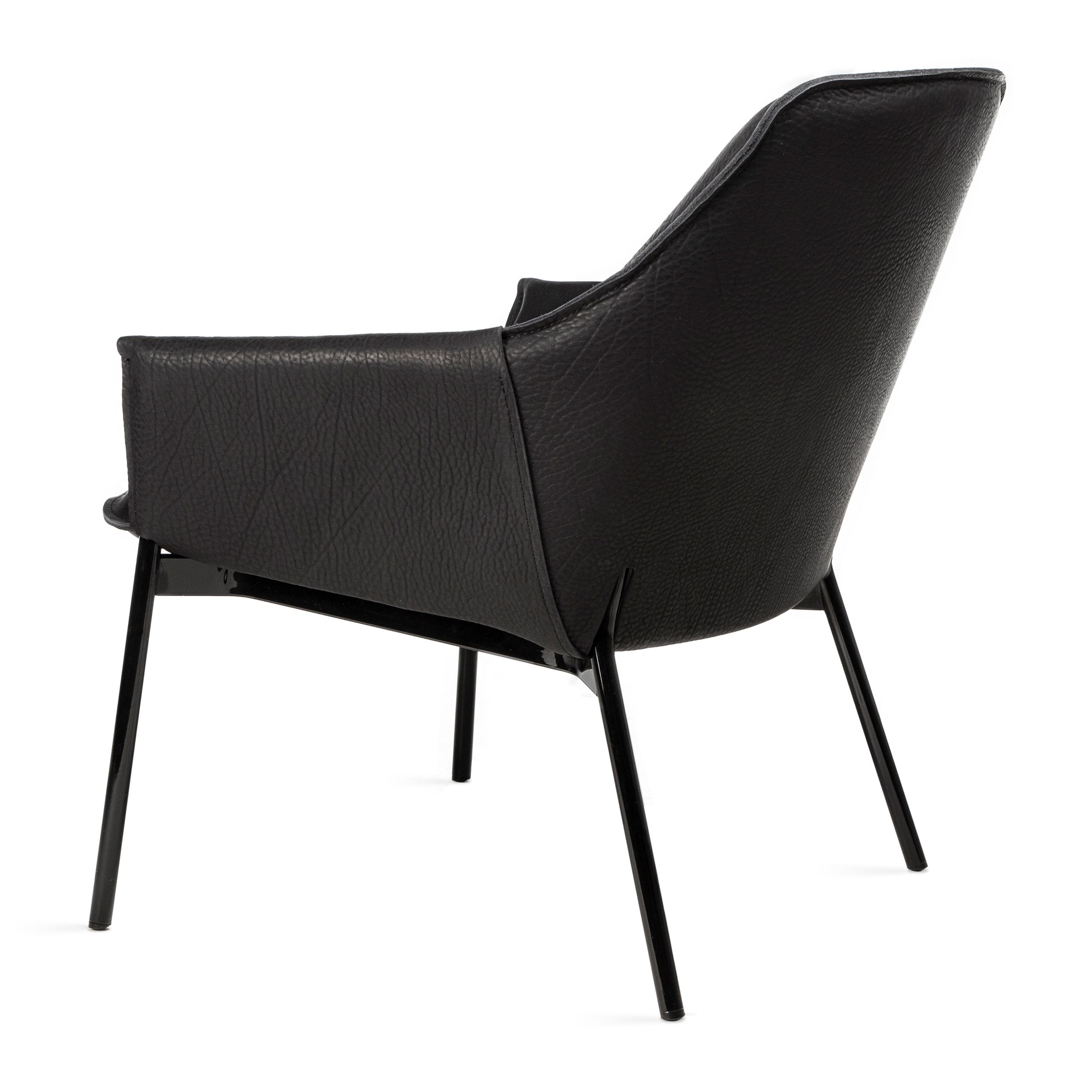 Zu sehen ist in Ansicht von schräg hintern ein moderner schwarzer Ledersessel, Modell Grace Lounge Lowback von Freifrau, vor einem weißen Hintergrund. Der Sessel hat hohe schwarze Metallbeine und schlanke Armlehnen.