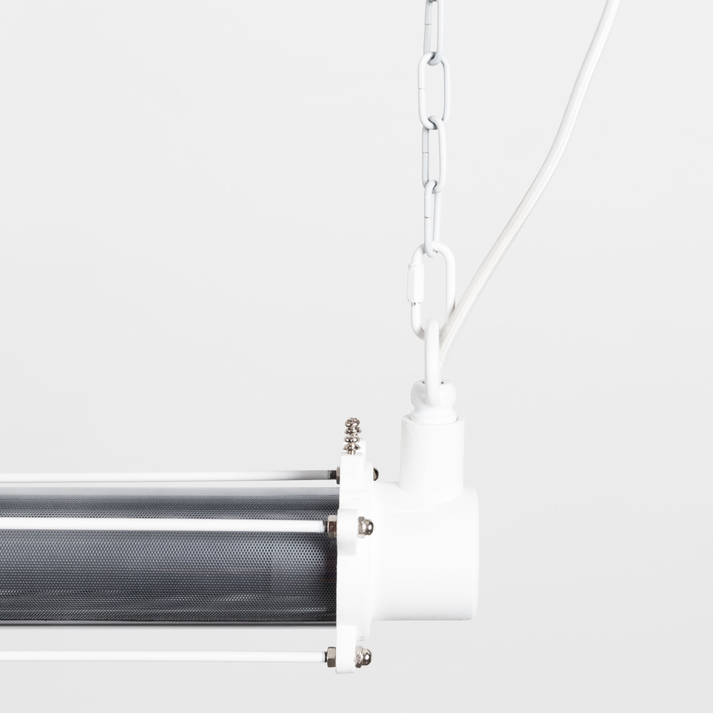 Nahaufnahme der rechten Endkappe einer weißen Röhrenlampe mit Gliederketten-Aufhängung und innenliegendem Lochblech-Diffusor.