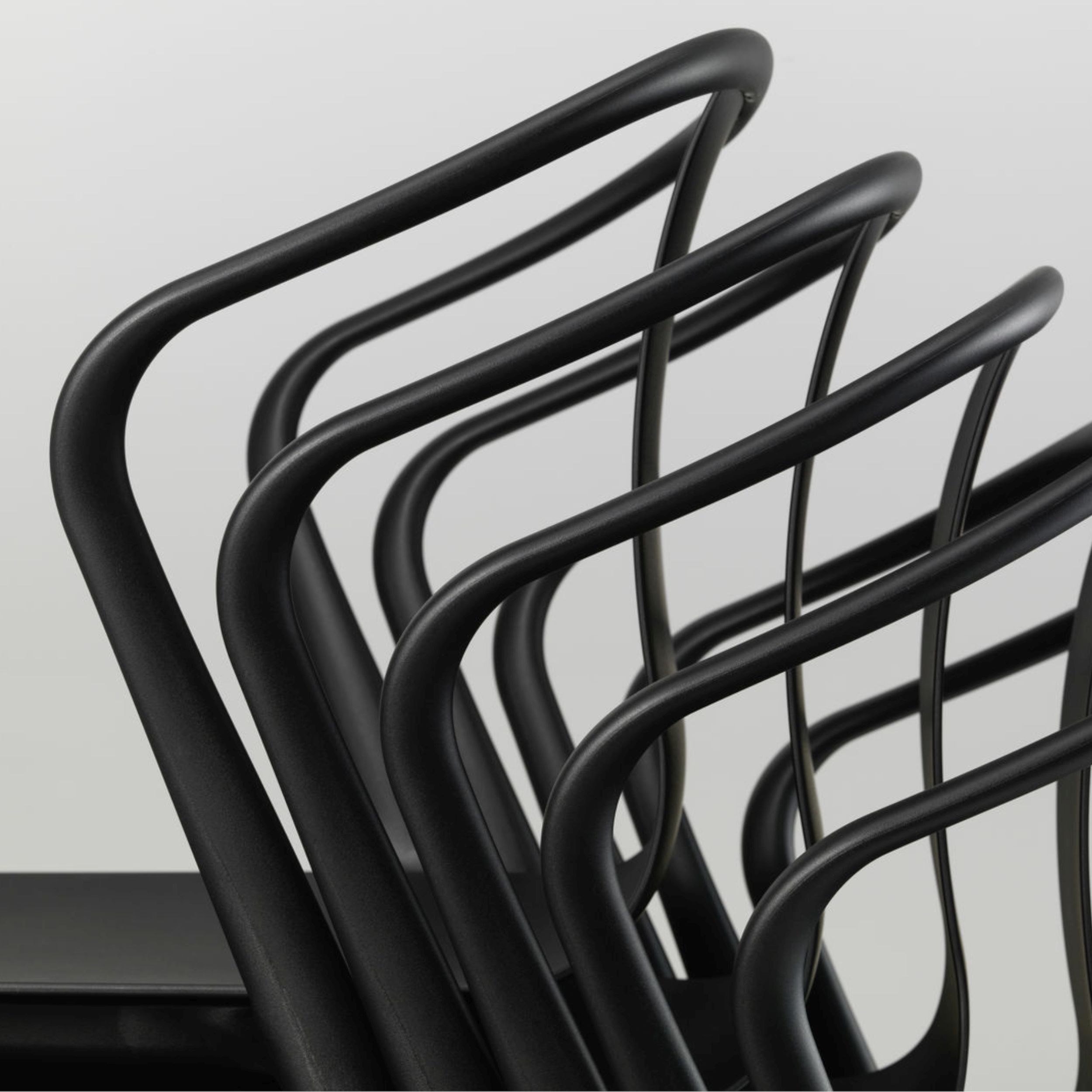 Stapelbarer Gartenstuhl Belleville Armchair aus schwarzem Kunststoff. Detailbild Stühle gestapelt.