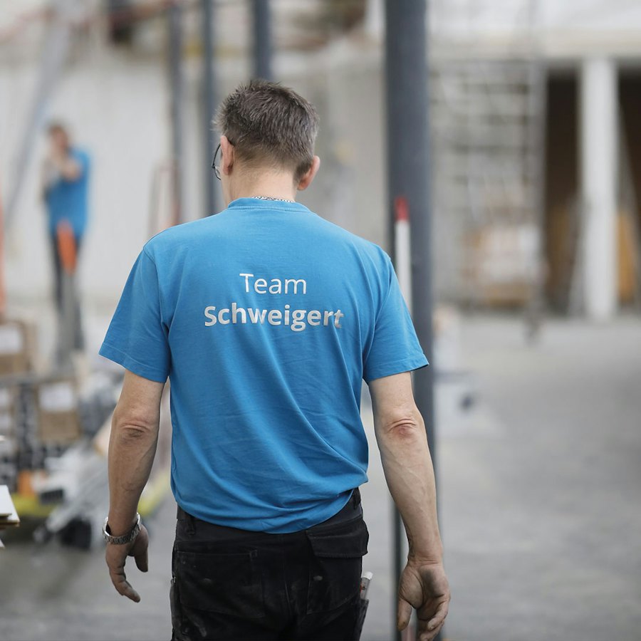 Mitarbeiter im blauen Team-Schweigert-Shirt von hinten in einem Raum im Umbau