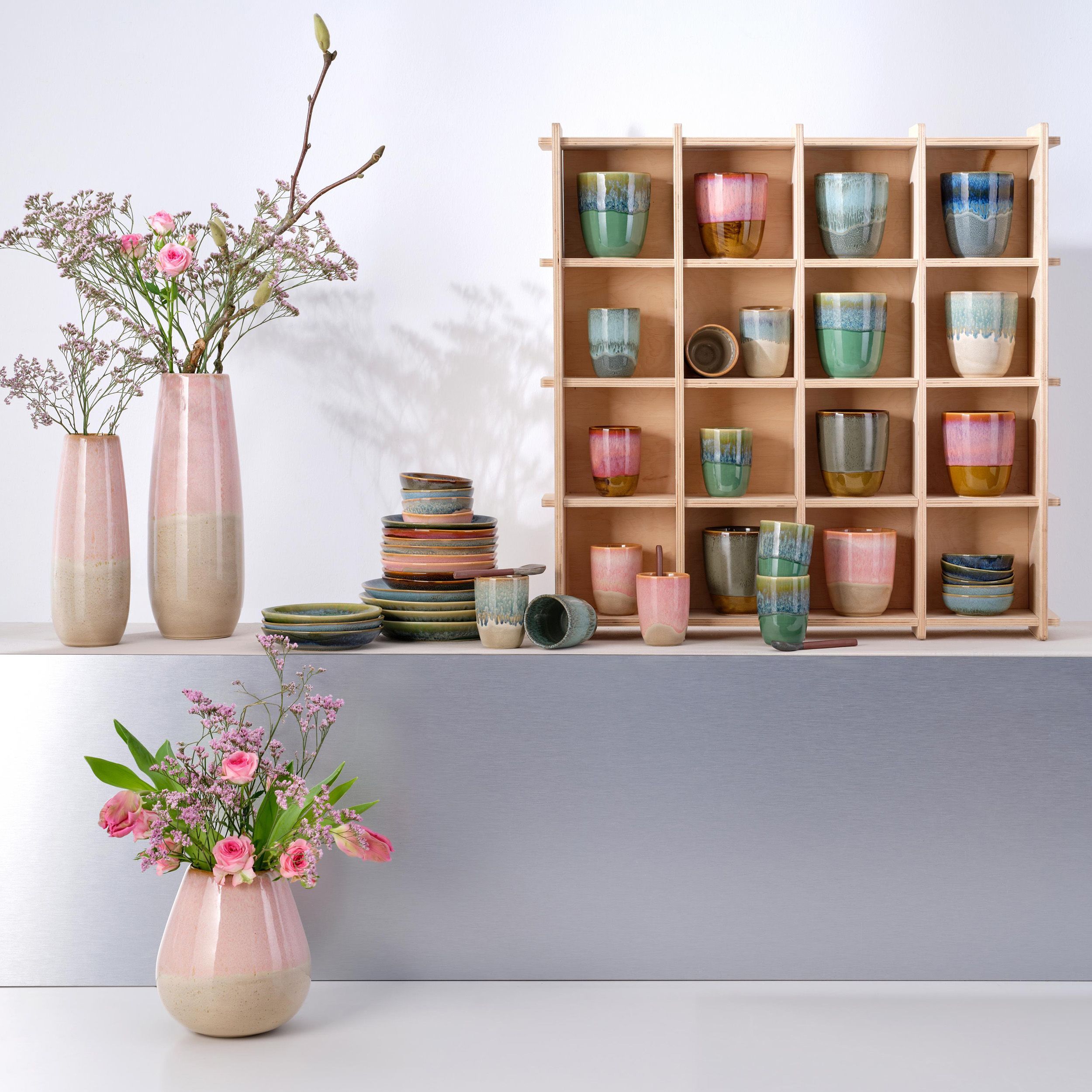 Cup Il Capriccio von Asa in verschiedenen Farben dekoriert in einem Regal und verschiedenen Accessoires stehend auf einer Fläche mit Vasen und Blumen dekoriert.
