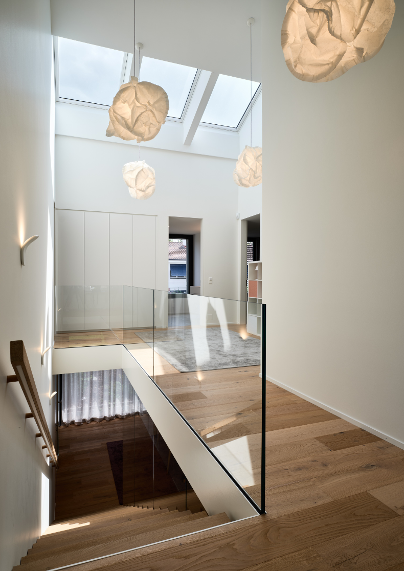 Treppenhaus mit Glasgeländer und Pendelleuchten