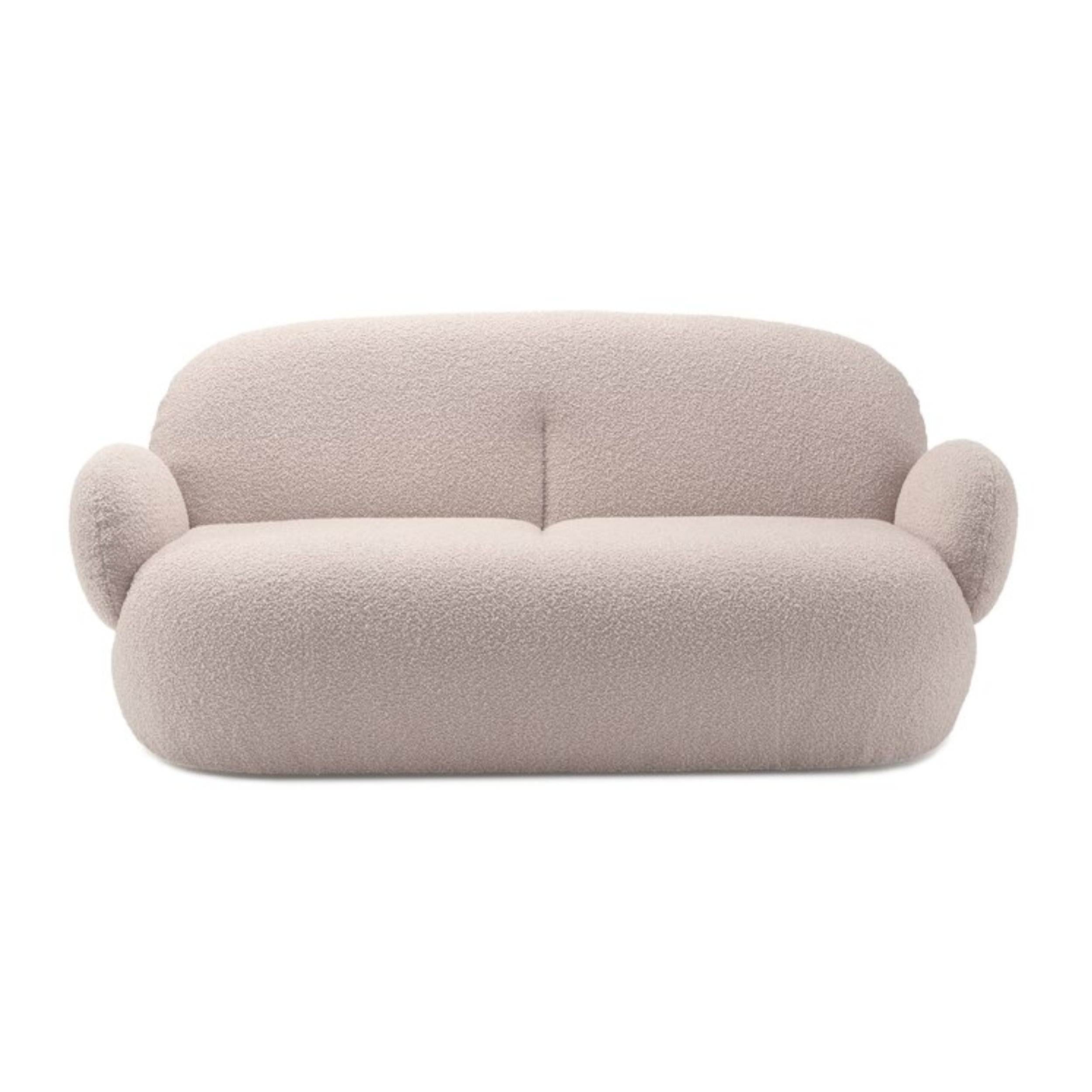 Zu sehen ist in frontaler Ansicht ein rundliches, helles Sofa mit Stoffbezug, Modell Nana von Freifrau, vor einem weißen Hintergrund.
