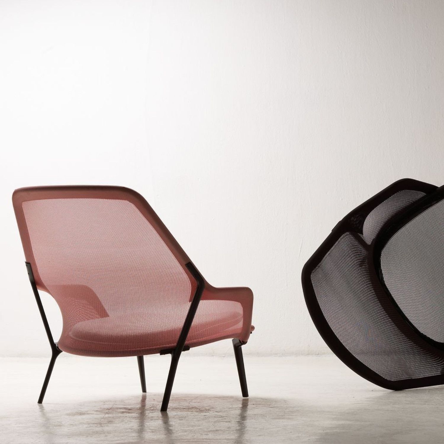 Slow Chair und Ottoman von Vitra in rosa Stricktex mit dunkel beschichtetem Gestell als Milieubild von hinten.