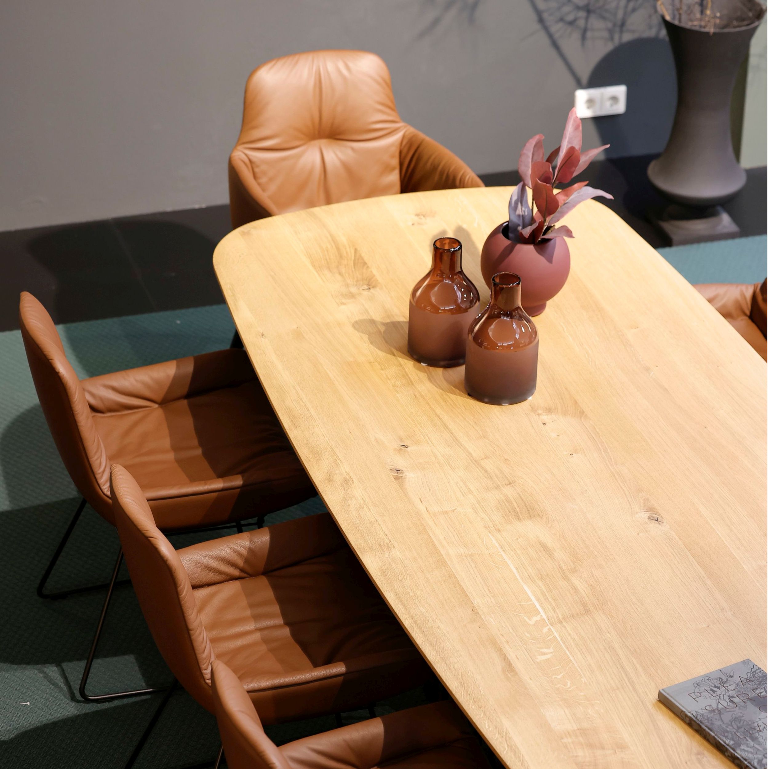 Ein eleganter Holztisch umgeben von Leya Armchairs von Freifrau, perfekt für gemütliche Zusammenkünfte oder kreative Meetings.  
