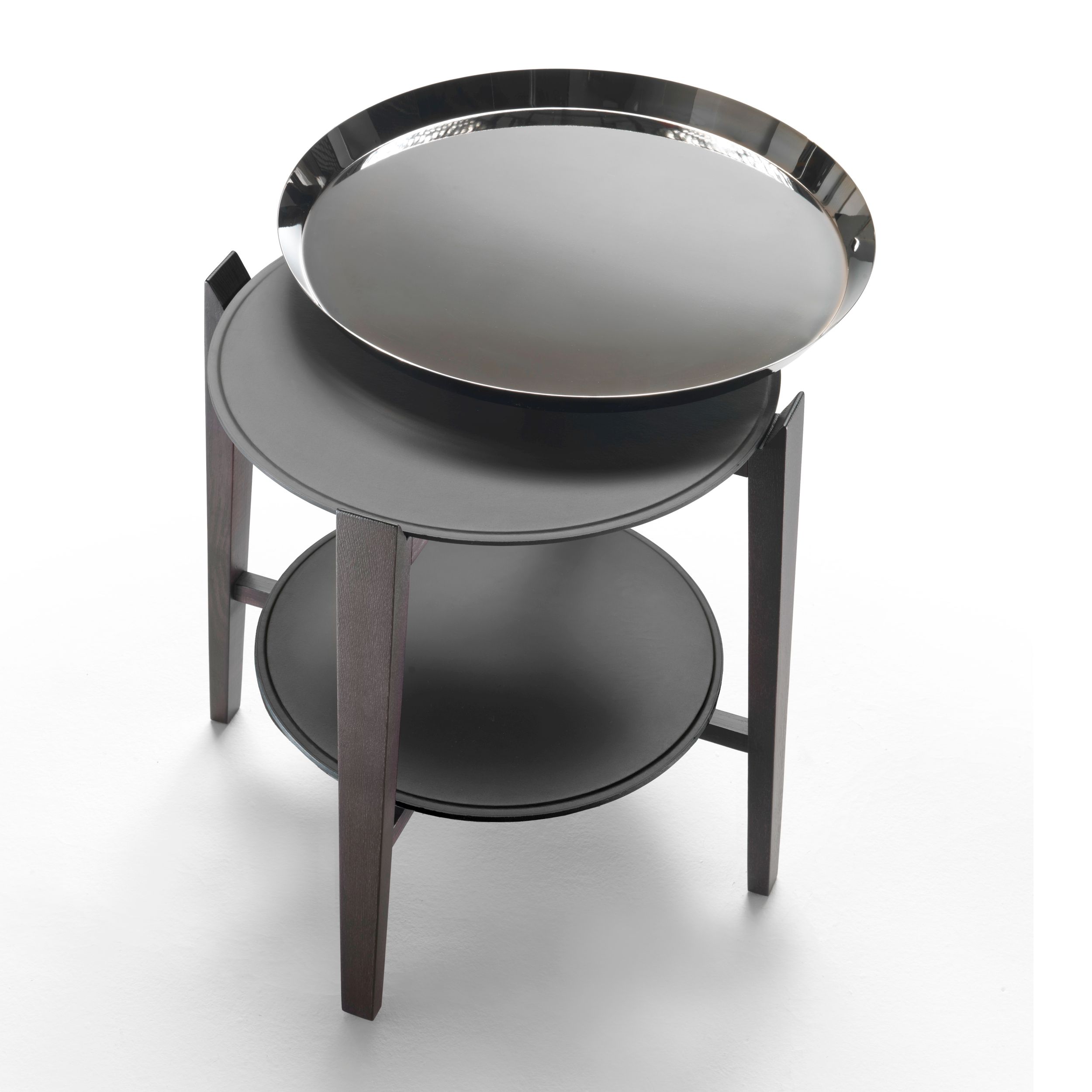 Ein runder Beistelltisch mit Holzgestell und zwei Ebenen, Modell Cabaré von Flexform, in Ansicht von schräg oben vor einem weißen Hintergrund. Auf der oberen Ebene ist seitlich verschoben ein rundes Metalltablett platziert.