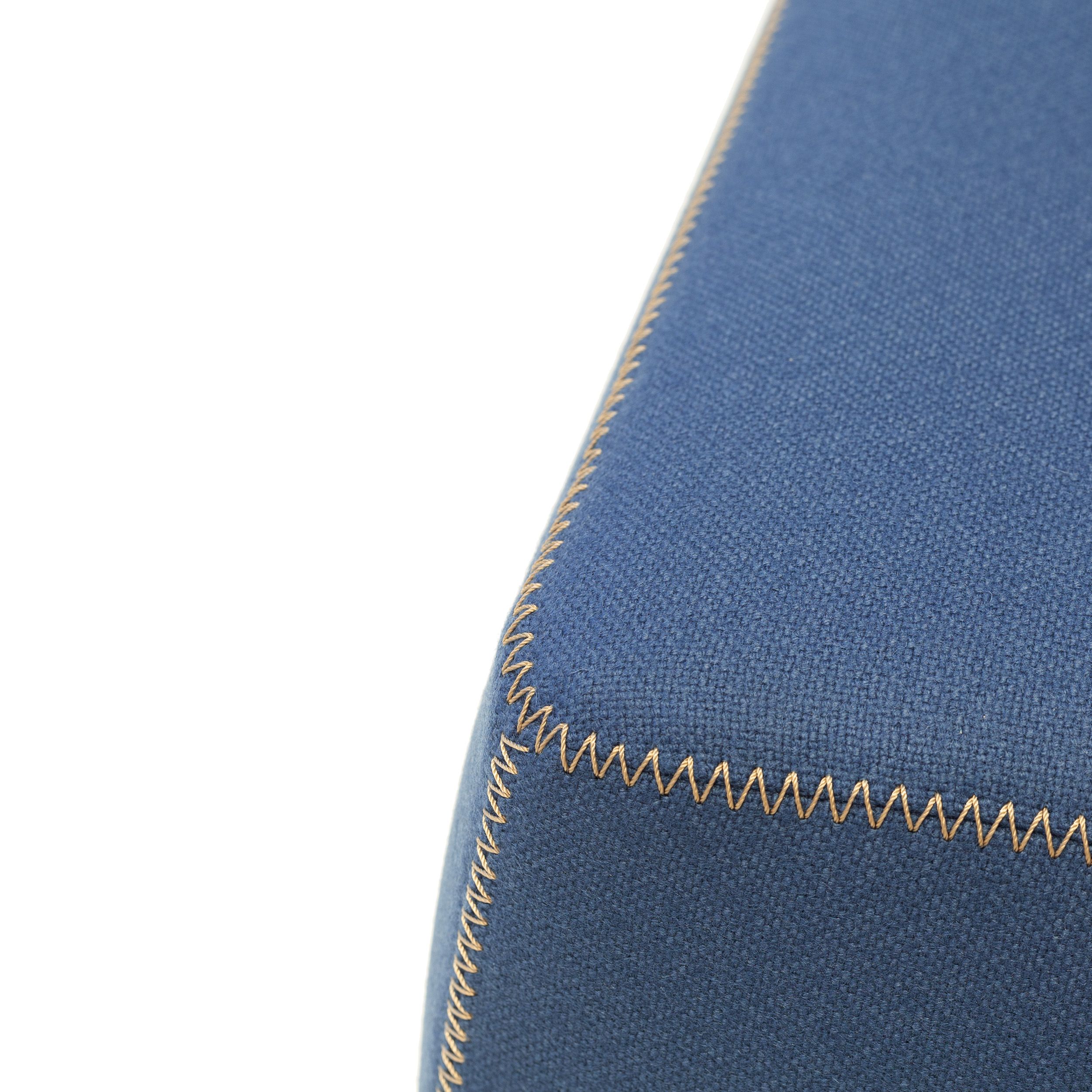 Zu sehen ist einer Detailaufnahme die helle Zig-Tag-Naht auf blauem Stoffbezug eines Sofas Bend von B&B Italia.