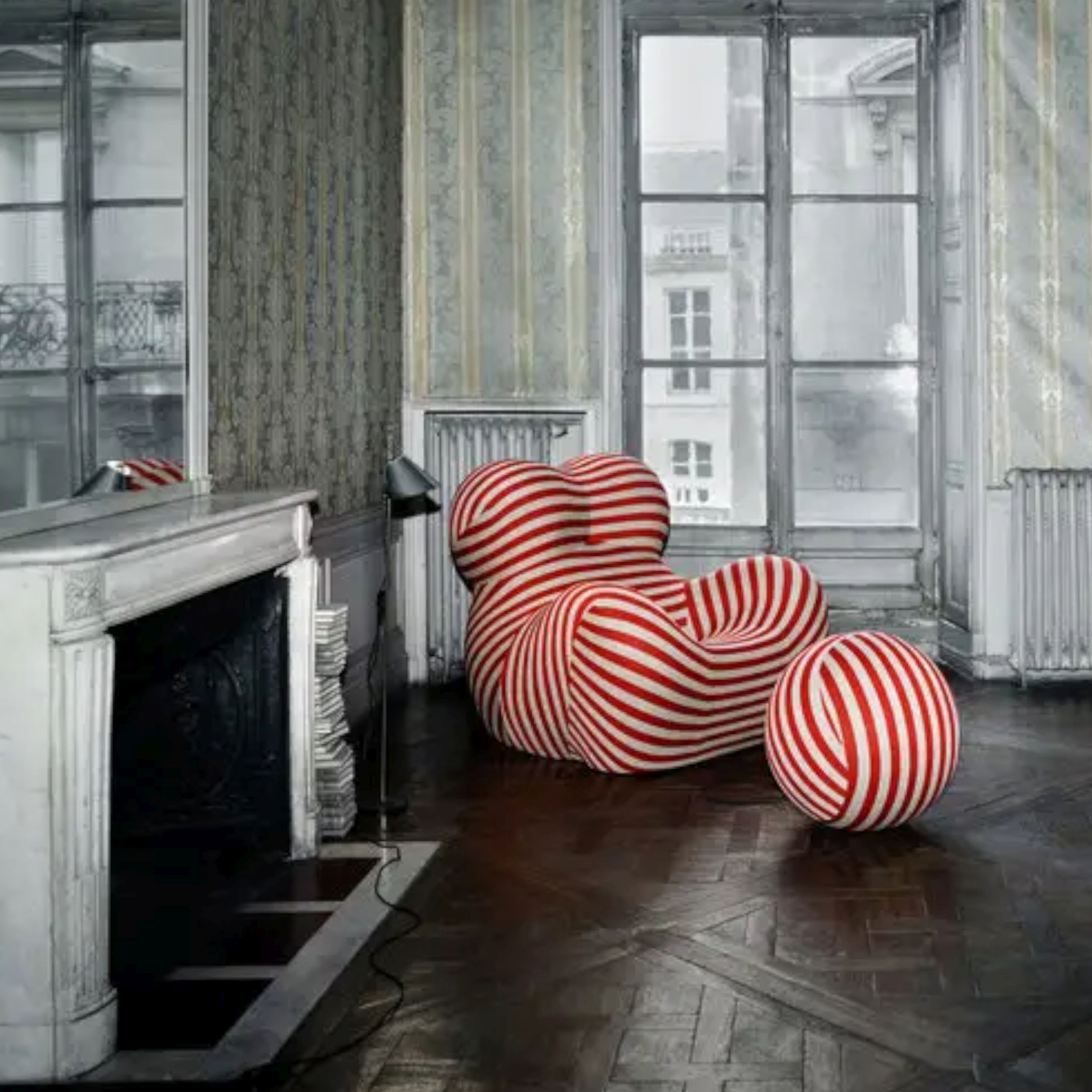Orange-beige gestreifter Sessel Up von B&B Italia mit kugelförmigem Hocker in einem historischen Raum mit weißem Marmorkamin und dunklem Parkettboden.