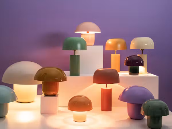 Bunte Pilz-Tischleuchten auf Podesten vor lila Wand