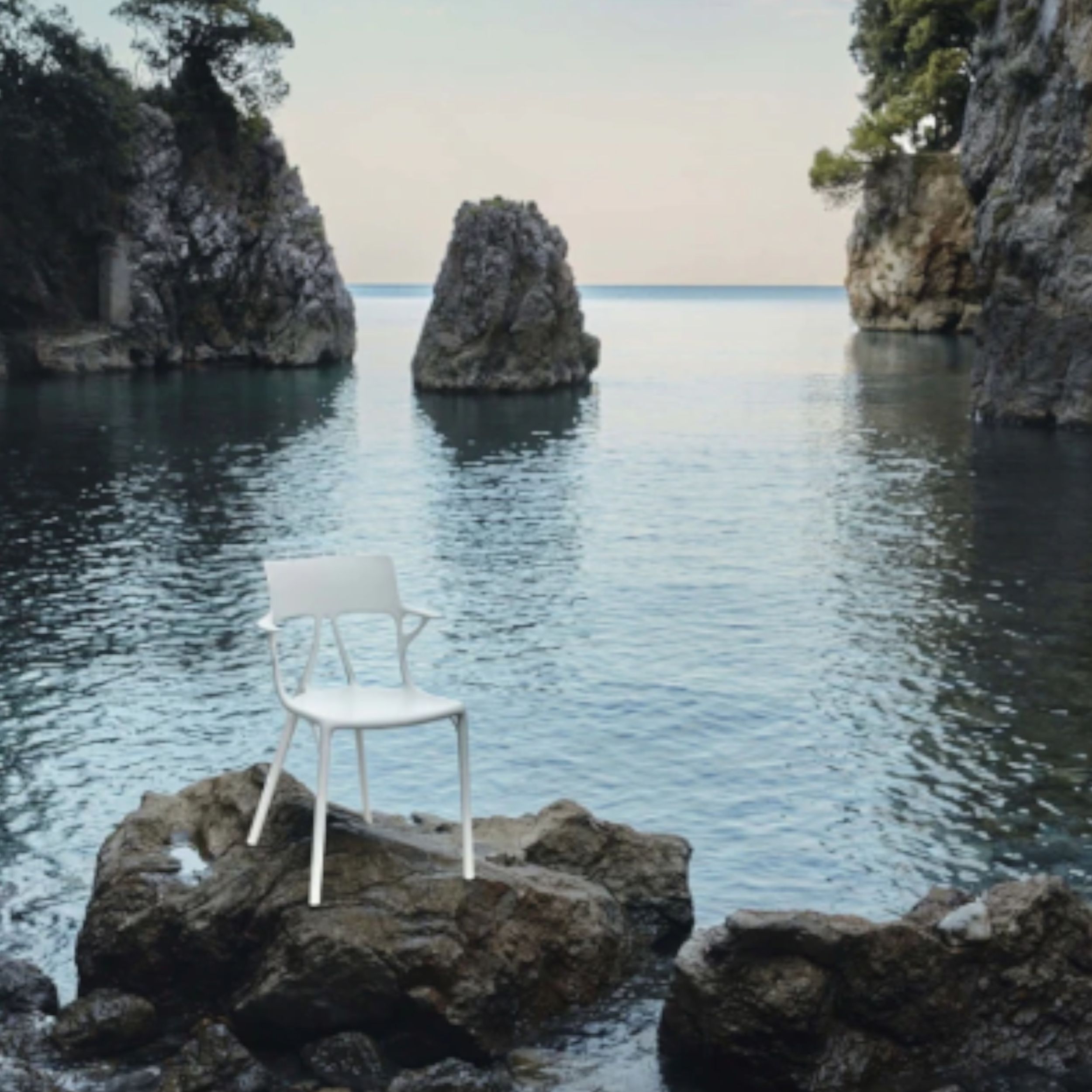 Gartenstuhl A.I. von Kartell in weiß im Milieubild auf Felsen am Meer.