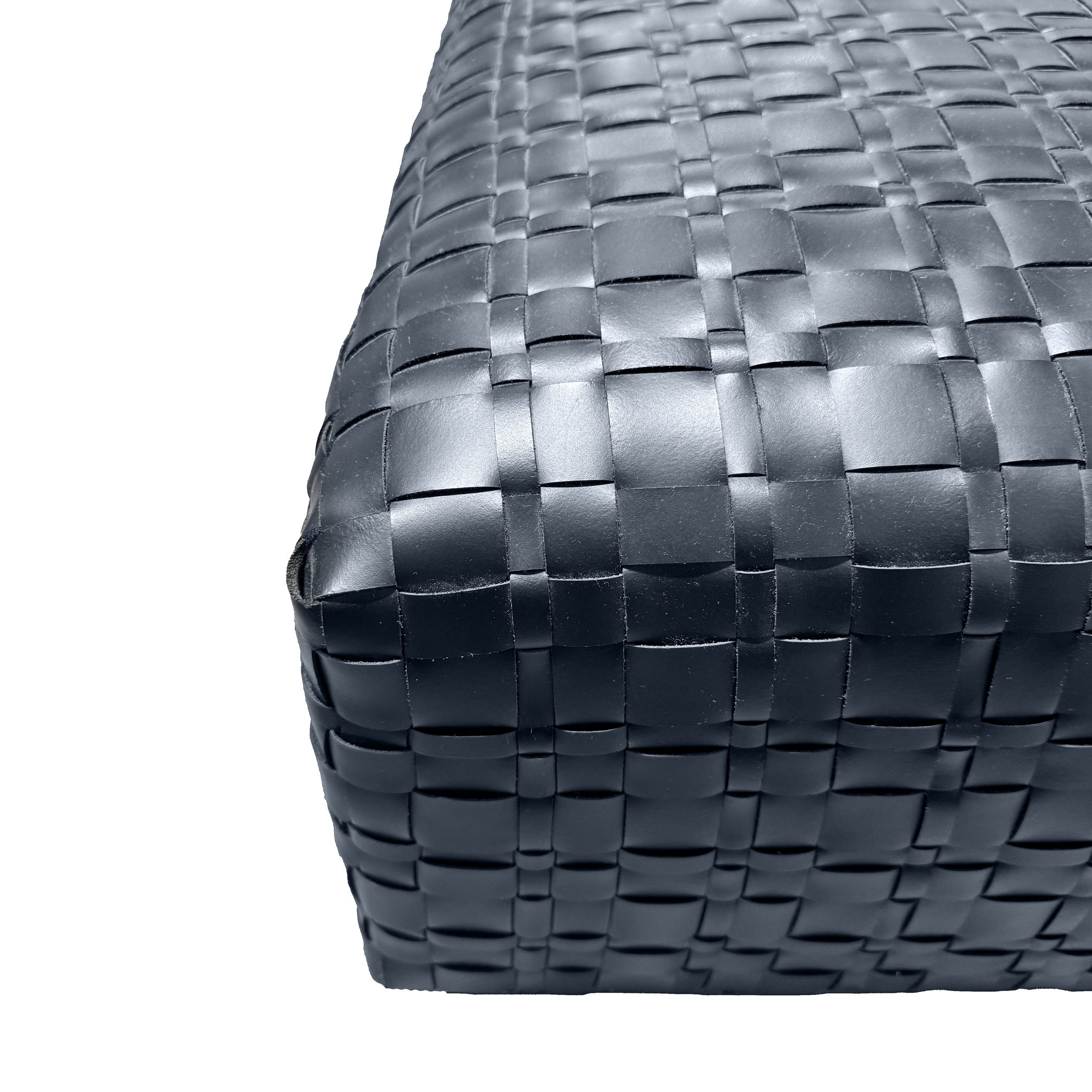 Zu sehen ist in einer Nahaufnahme eine Ecke des Polsterhockers Bangkok von Flexform mit seiner Oberfläche aus geflochtenen, schwarzen Lederriemen.