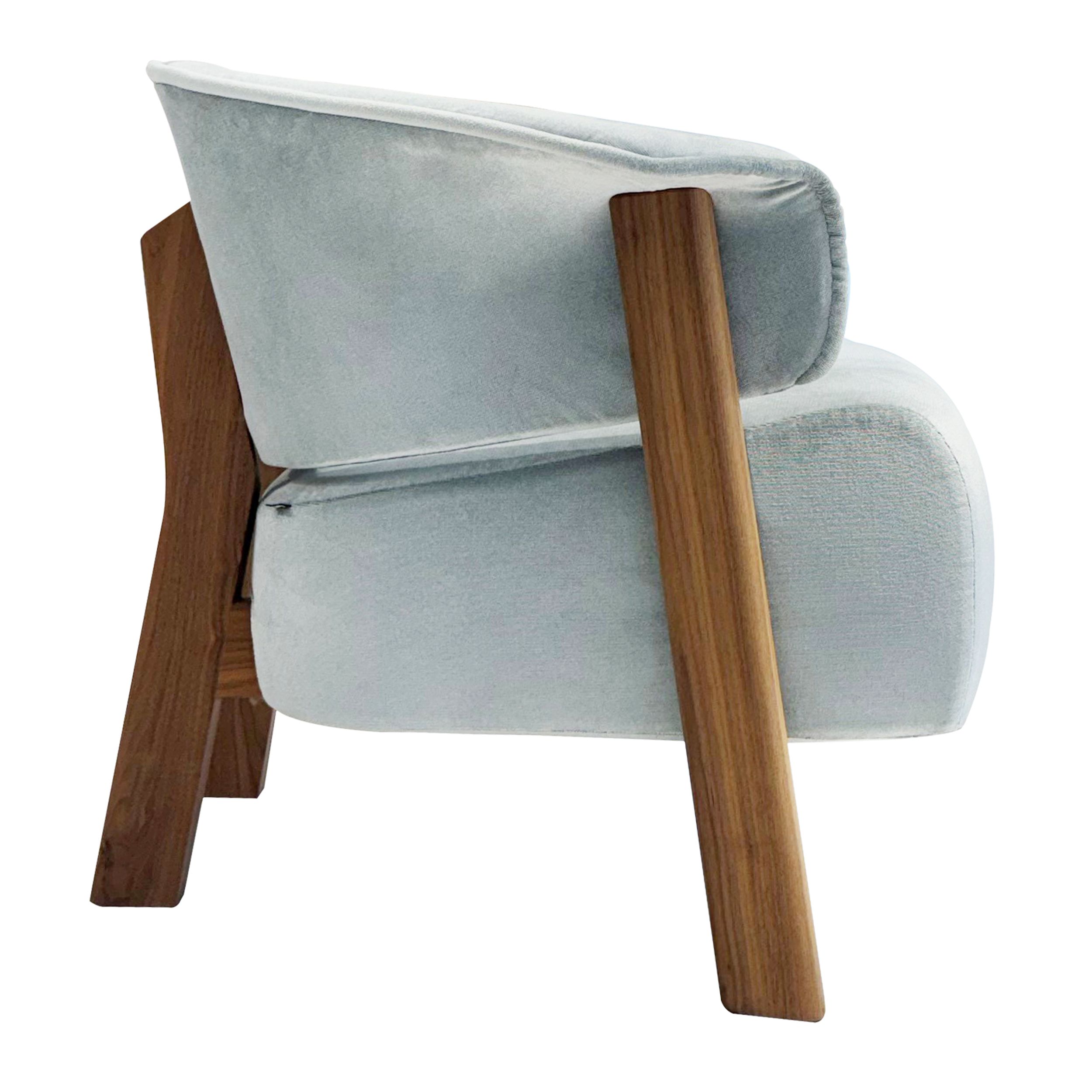 Sessel Back-Wing Armchair Cassina mit hellblauem Bezug und Nussbaumgestell in seitlicher Ansicht vor einem weißen Hintergrund.