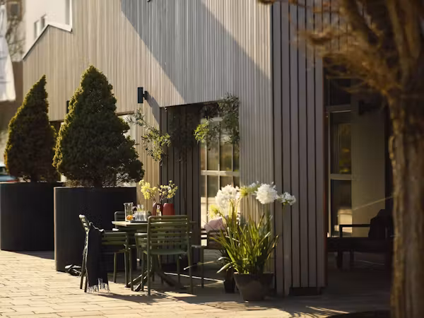 Terrasse mit Gartentisch, Pflanzkübeln und Holzfassade