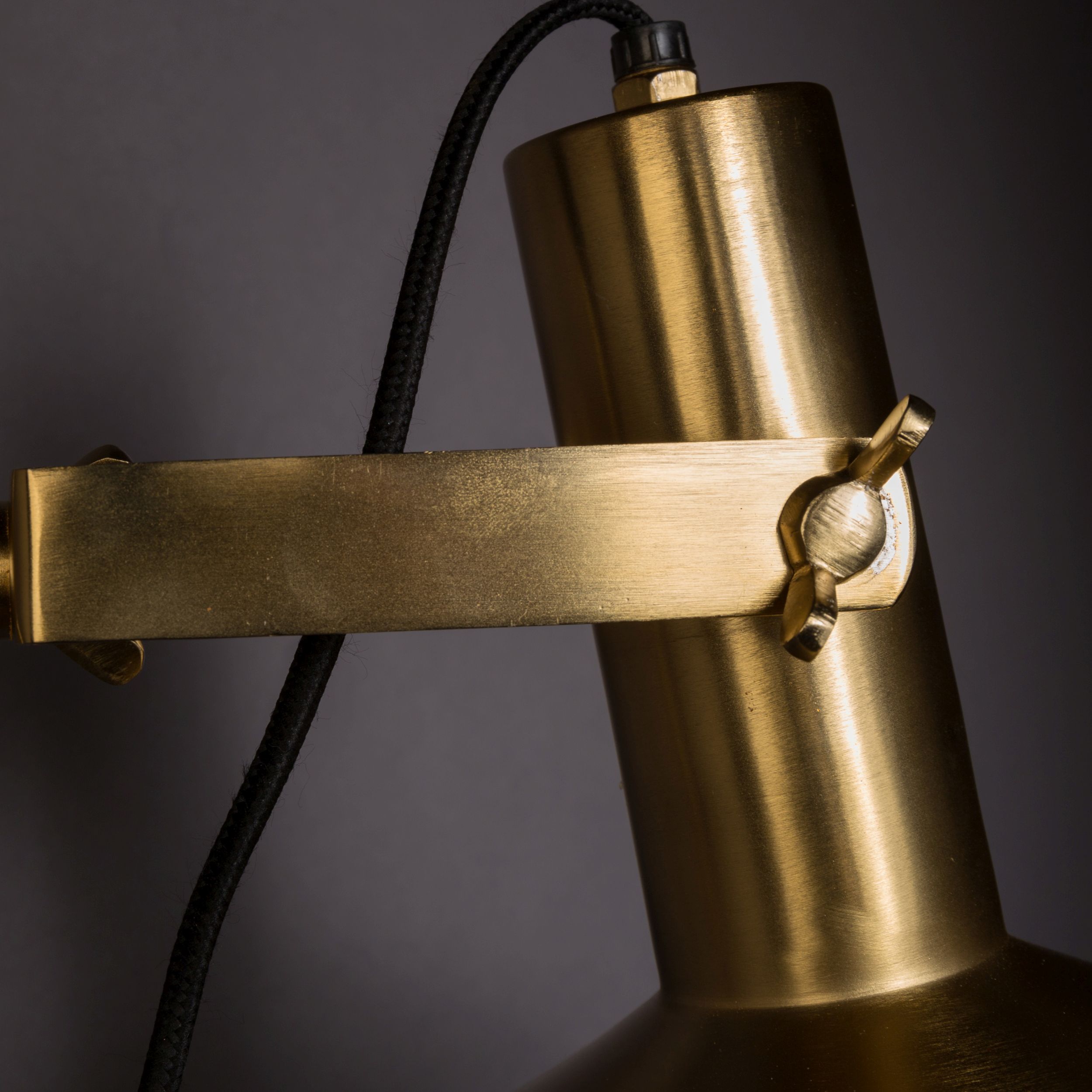 Detailansicht des goldenen Befestigungsarms einer verstellbaren Industrial-Wandlampe aus Metall.