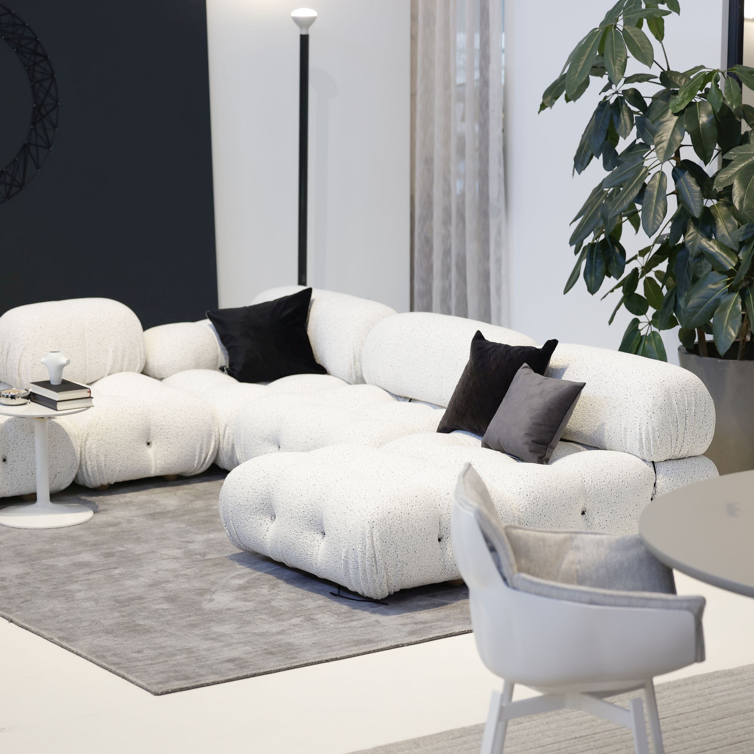 Auf dem Bild sieht man das modulare Sofamodell Camaleonda von B&B Italia in einem modernen Studio. Das Sofa ist mit weißem Stoff bezogen und steht auf einem grauen Teppich.