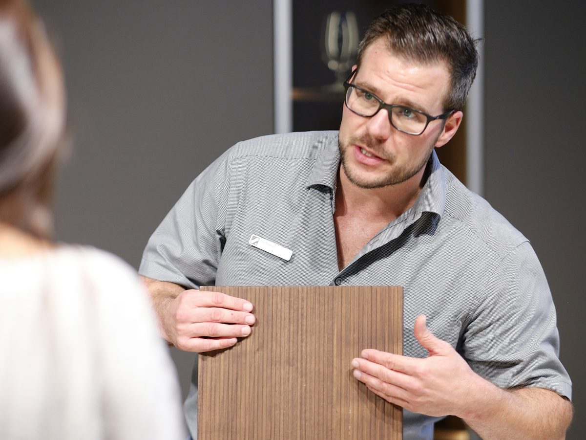 Küchenfachberater erklärt einer Kundin Holz als Oberflächenmaterial