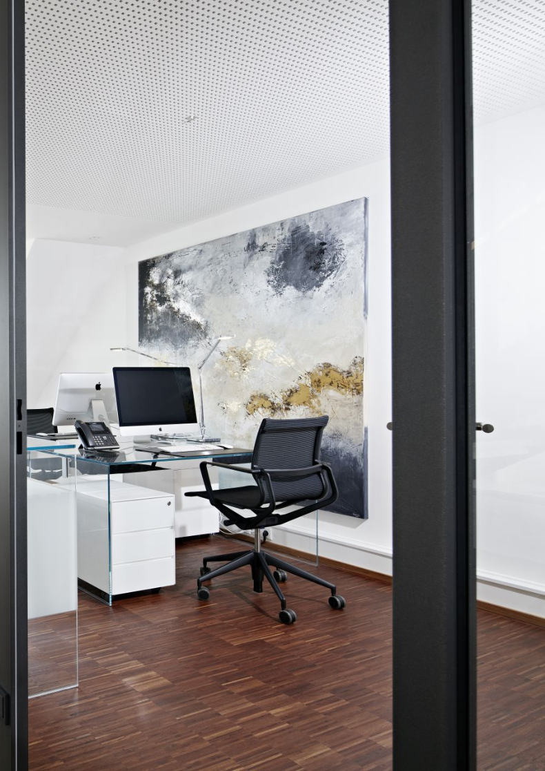 Büro mit Schreibtisch und Bürostuhl hinter einer Glastür