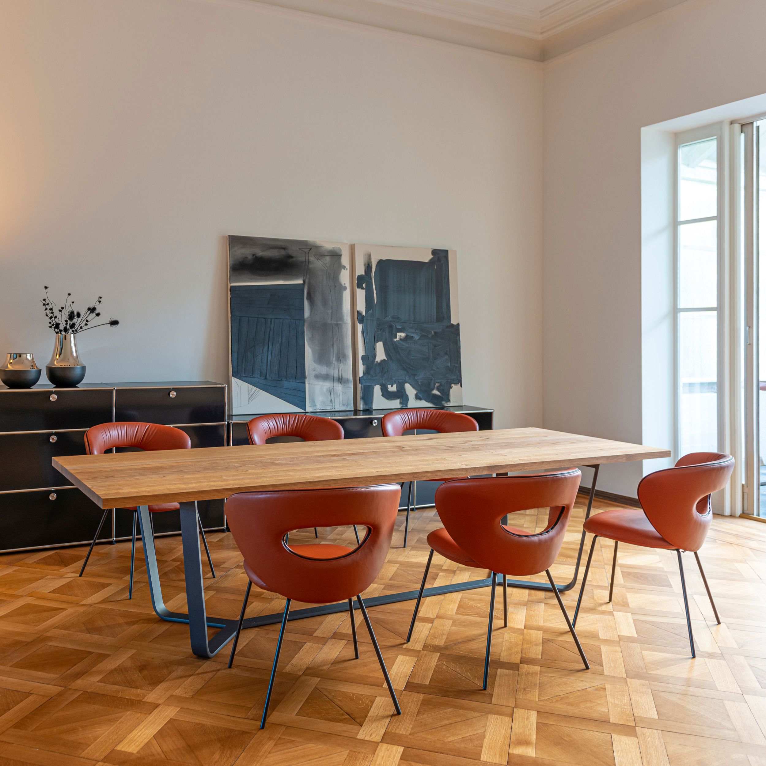 Esszimmer mit einem Tisch Axis von Asco und Stühlen Alice von KFF in orangefarbenem Leder, elegant und modern eingerichtet.  